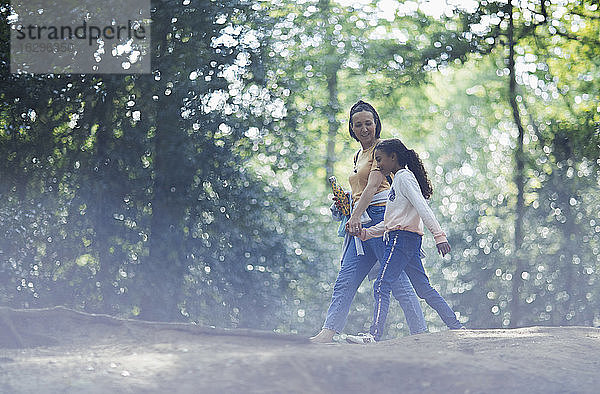 Mutter und Tochter beim Händchenhalten beim Wandern im Sommerwald