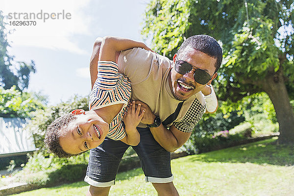 Porträt spielerischer Vater und Sohn im sonnigen Hinterhof