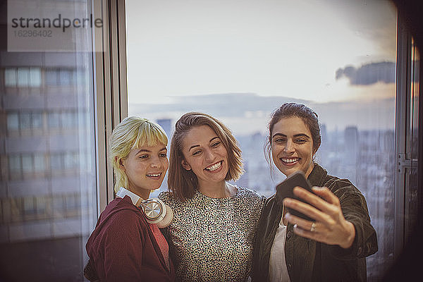 Lächelnde Geschäftsfrauen nehmen Selbstgefälligkeit am Fenster eines Hochhausbüros