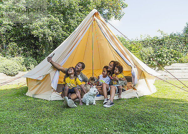 Glückliche Familie nimmt Selfie im Zelt im Sommerhinterhof