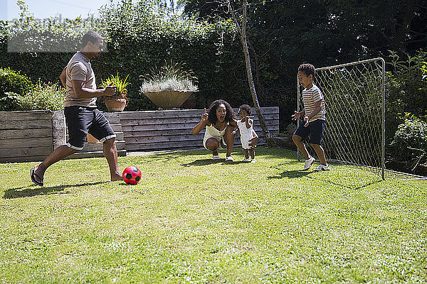 Familie spielt Fussball im sonnigen Sommerhinterhof