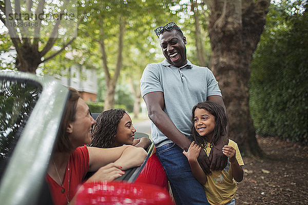 Glückliche Familie lacht über Cabrio in der Einfahrt