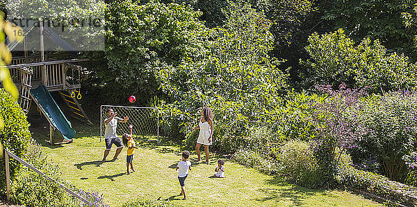 Familie spielt Fussball im sonnigen Sommerhinterhof