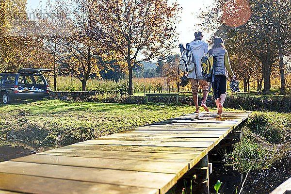 Barfüßiges junges Paar beim Spaziergang am sonnigen Herbstufer des Sees