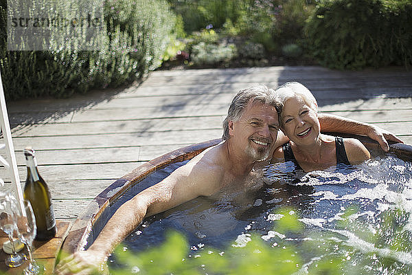 Porträt eines glücklichen älteren Paares  das sich im Whirlpool auf der sonnigen Terrasse entspannt