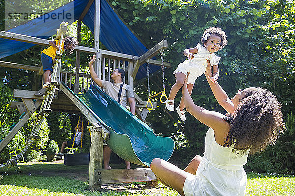 Glückliche Familie spielt auf einem Spielplatz in einem sonnigen Sommerhinterhof