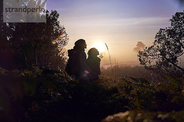 Silhouette eines ruhigen jungen Paares  das bei Sonnenuntergang eine Wanderung in der Natur genießt