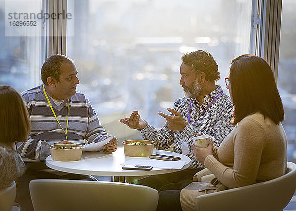 Geschäftsleute unterhalten sich und essen zu Mittag in der Büro-Cafeteria