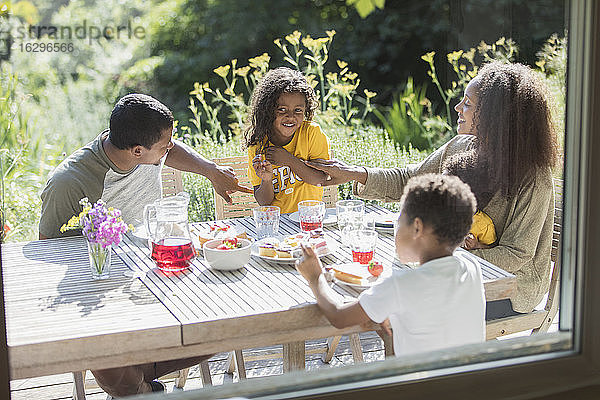 Glückliche Familie genießt das Mittagessen auf der sonnigen Sommerterrasse