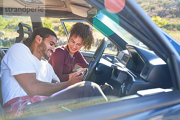 Glückliches junges Paar genießt Autoreise im sonnigen Auto