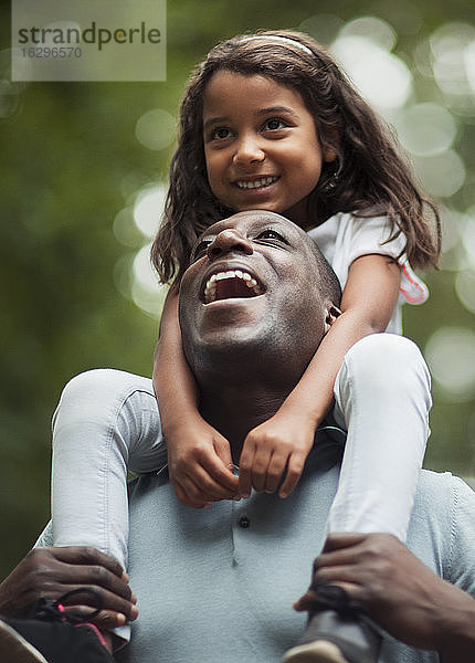 Glücklicher Vater trägt Tochter auf den Schultern