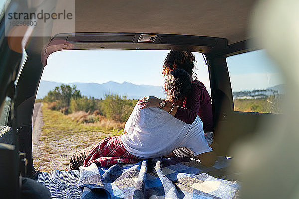Zärtliches junges Paar genießt sonnige Aussicht auf die Natur vom Heck des Autos