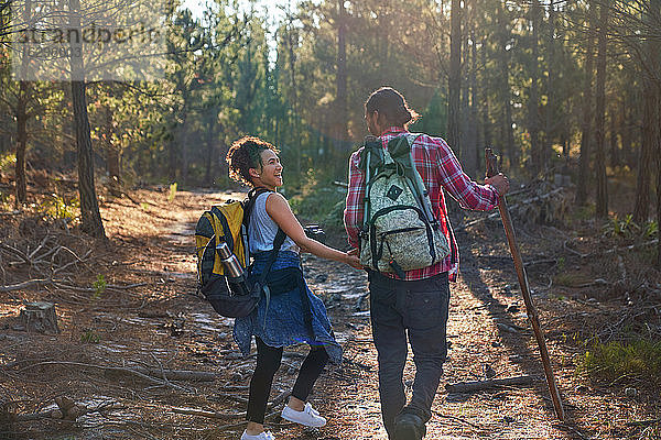 Glückliches junges Paar mit Rucksäcken wandert in sonnigen Wäldern