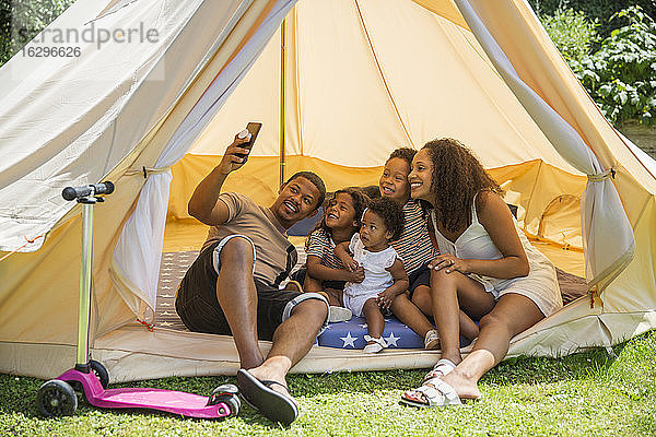 Fröhliche Familie nimmt sich mit Fotohandy im Sommerzelt ein