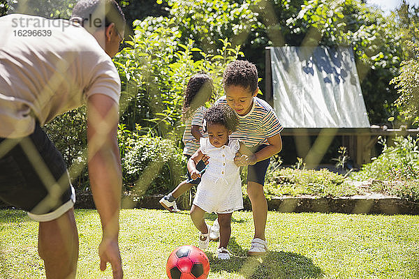 Familie spielt Fussball im sonnigen Sommerhinterhof