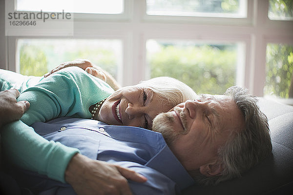 Glückliches Seniorenpaar kuschelt am sonnigen Fenster