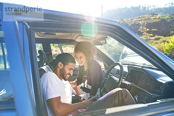 Glückliches junges lachendes Paar auf Autoreise im sonnigen Auto