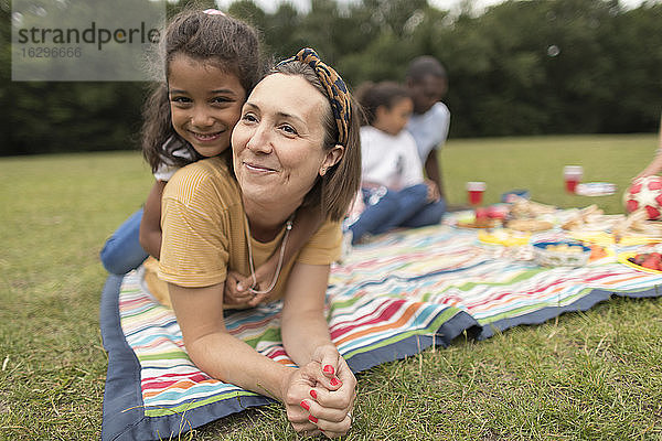 Porträt einer glücklichen Mutter und Tochter  die sich auf einer Picknickdecke im Park entspannen