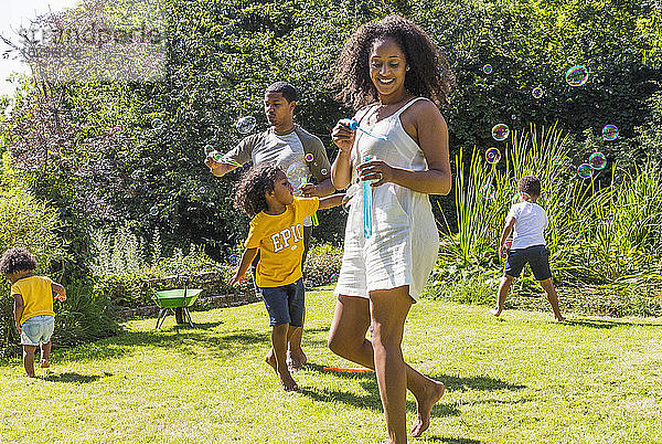 Fröhliches Familienspiel und Blasenblasen im sonnigen Sommergarten