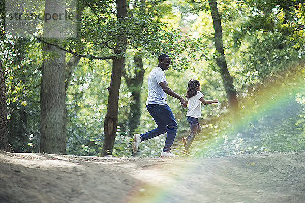 Glücklicher Vater und Tochter laufen auf Wanderwegen in Sommerwäldern