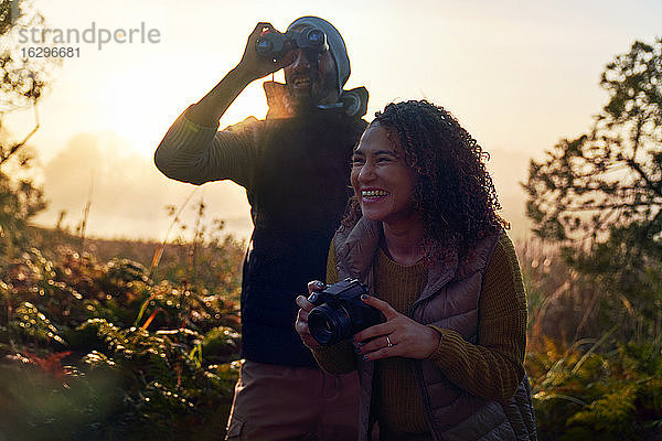 Glückliches junges Wanderpaar mit Kamera und Fernglas in der Natur