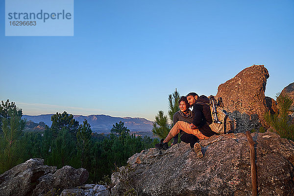 Junges Wandererpaar entspannt sich am Felsen und geniesst den Sonnenuntergang