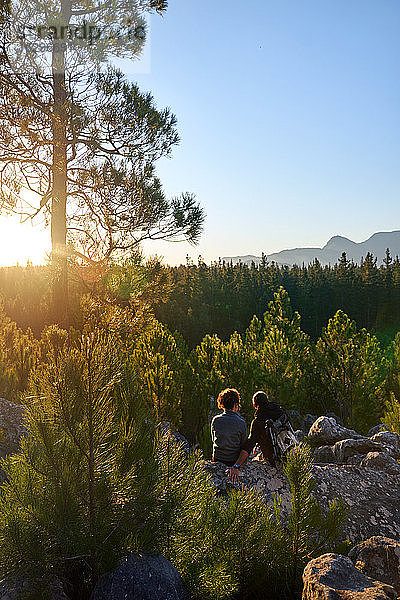 Junges Wandererpaar geniesst bei Sonnenuntergang sonnige Aussicht auf Bäume im Wald