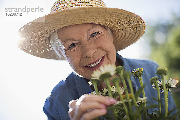 Nahaufnahme Porträt einer glücklichen älteren Frau beim Gärtnern mit Strohhut