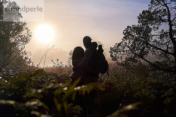 Silhouette eines ruhigen jungen Paares  das den Sonnenuntergang in der Natur genießt