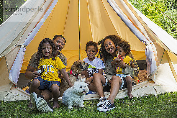 Porträt einer glücklichen Familie mit Hunden im Camping-Zelt