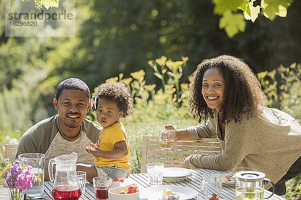 Portrait glückliche Familie beim Mittagessen im Sommergarten