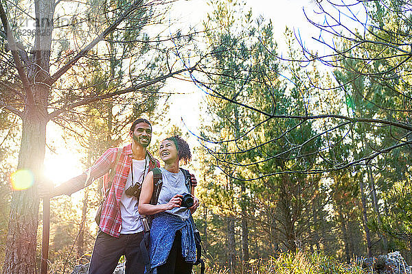 Glückliches junges Paar wandert mit Kamera und Fernglas in sonnigen Wäldern