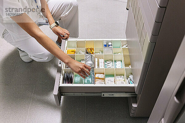 Ärztin sucht Medikamente in der Schublade einer Apotheke