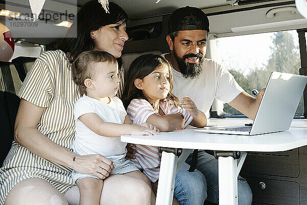 Familie führt Videogespräch über Laptop  während sie im Van im Park sitzt