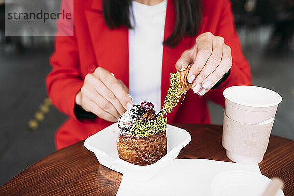 Mittelteil einer Geschäftsfrau  die in einem Café Kuchen isst