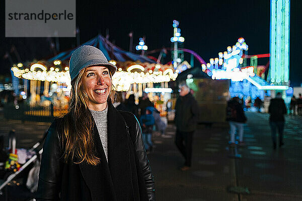 Lächelnde Frau auf dem Rummelplatz im Winter