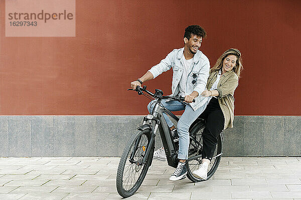 Glückliches Paar genießt Fahrt auf Elektrofahrrad in der Stadt