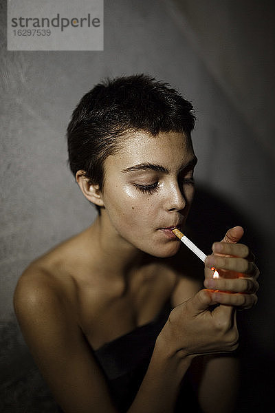 Frau zündet Zigarette an einer grauen Wand an