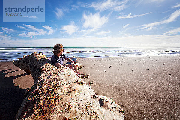 Neuseeland  Wanganui Strand  Junger Mann sitzt am Strand