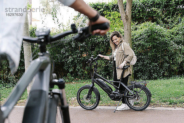 Lächelnde Frau mit Elektrofahrrad auf der Straße