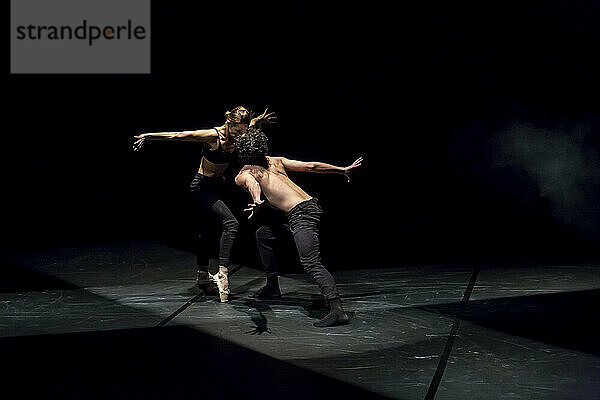 Tänzer und Tänzerin beim zeitgenössischen Ballett auf schwarzer Bühne