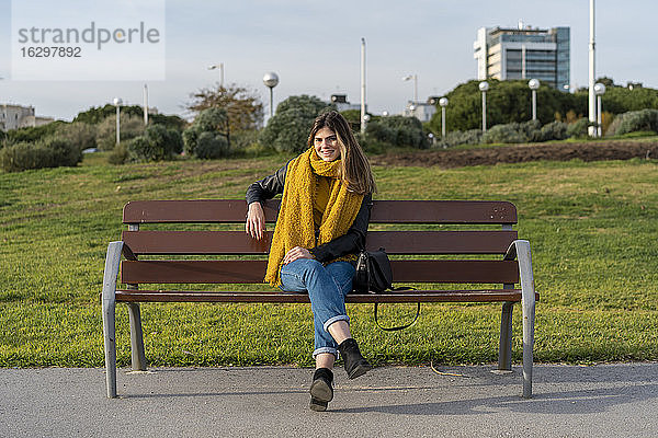 Junge Frau sitzt auf einer Bank im Park