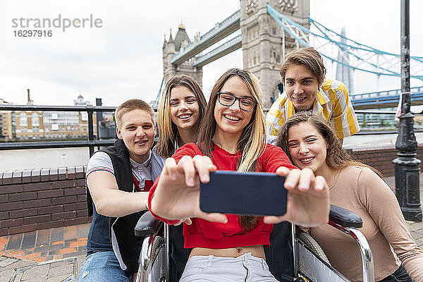 Glückliche junge Frauen und Männer machen ein Selfie mit der Tower Bridge im Hintergrund  London  UK