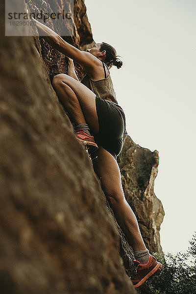Entschlossene Frau klettert auf einen Felsen im Wald