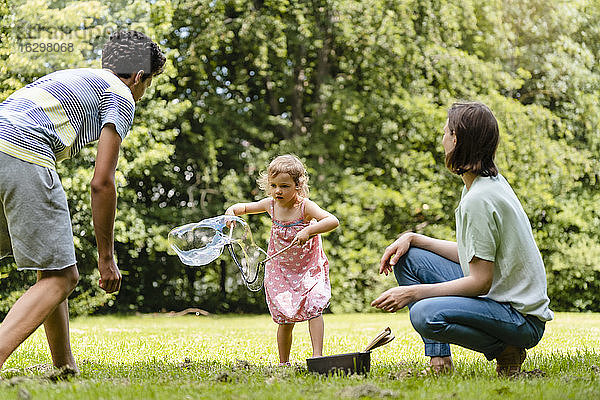Familie spielt mit Seifenblase im Park