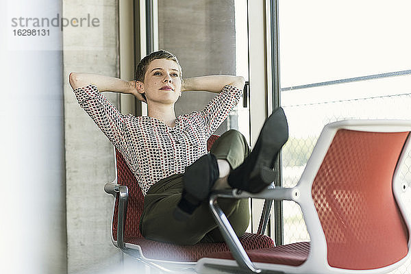 Entspannte Geschäftsfrau sitzt auf einem Stuhl im Büro und macht eine Pause