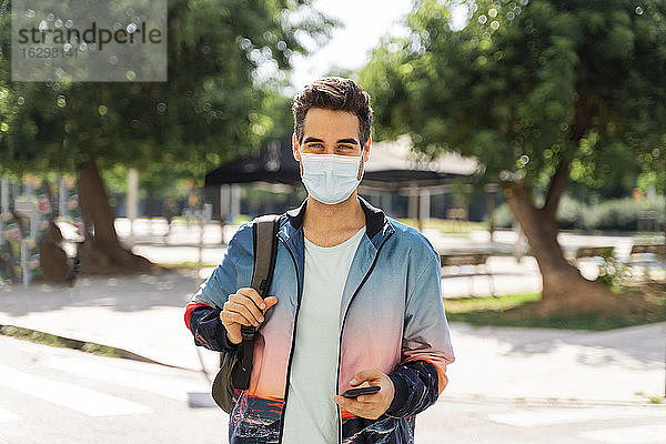 Mann mit Gesichtsmaske steht während COVID-19 in der Stadt