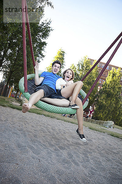 Jugendliches Paar schaukelt auf dem Spielplatz