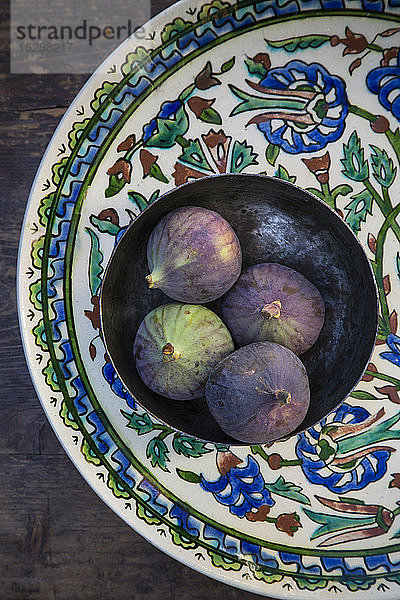 Schale mit vier Feigen (Ficus carica) auf traditionellem andalusischem Keramikteller  Studioaufnahme