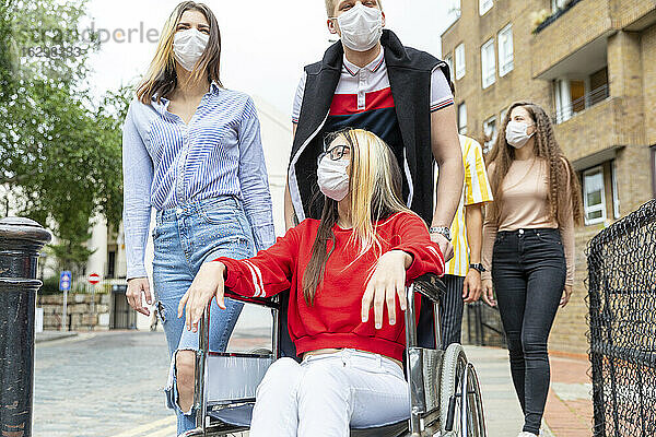 Männer und Frauen mit einer behinderten Freundin tragen in der Stadt Masken